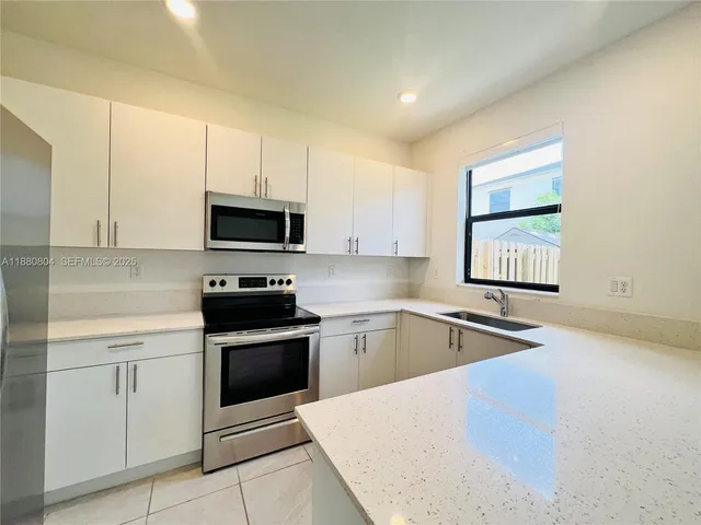 a kitchen with granite countertop white cabinets and black stainless steel appliances