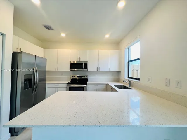 a kitchen with stainless steel appliances a refrigerator a sink a stove a microwave and island