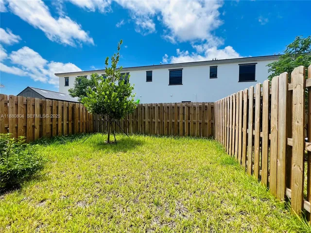 a view of backyard with potted plants and wooden fence