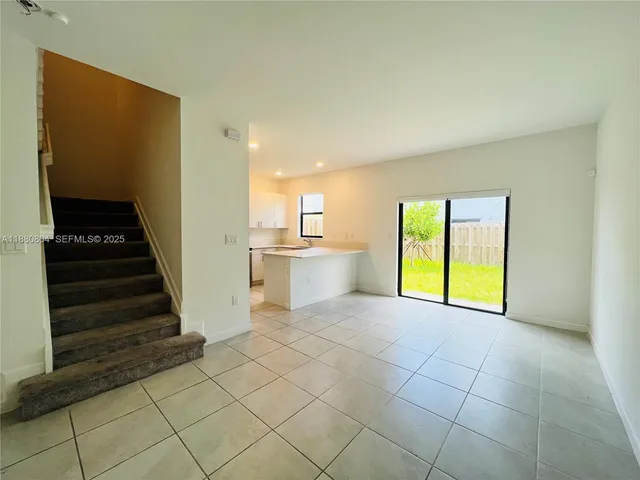 a view of an empty room with wooden floor and stairs