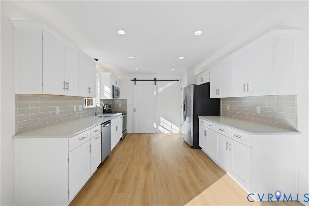 4255 Pierce Road Powhatan, VA 23139 - Photo 12 of 34 Kitchen with a barn door, white cabinetry, stainle