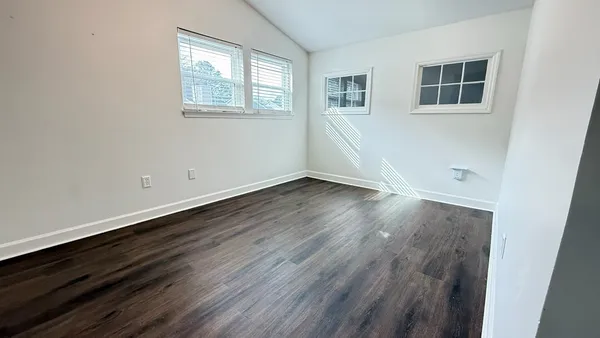 an empty room with wooden floor and windows