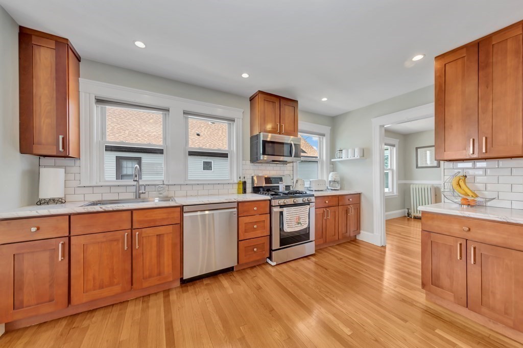 9-11 Locust Street, Unit 2 Winthrop, MA 02152 - Photo 13 of 41 a large kitchen with stainless steel appliances granite countertop a sink dishwasher stove and wooden cabinets