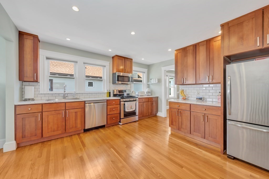 9-11 Locust Street, Unit 2 Winthrop, MA 02152 - Photo 14 of 41 a large kitchen with stainless steel appliances granite countertop a stove a sink dishwasher a refrigerator and white cabinets with wooden floor