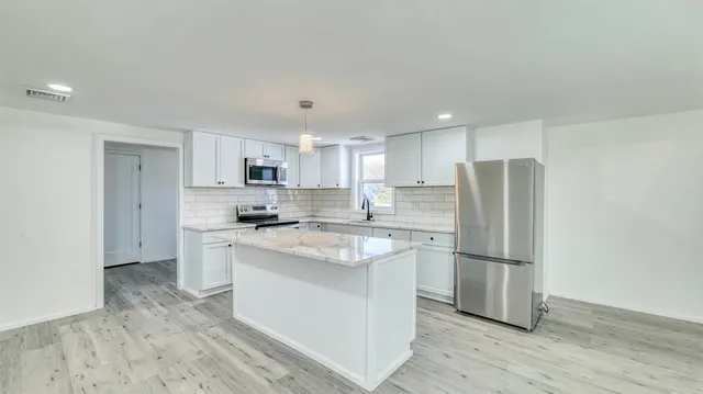 a kitchen with stainless steel appliances granite countertop a refrigerator and a stove top oven
