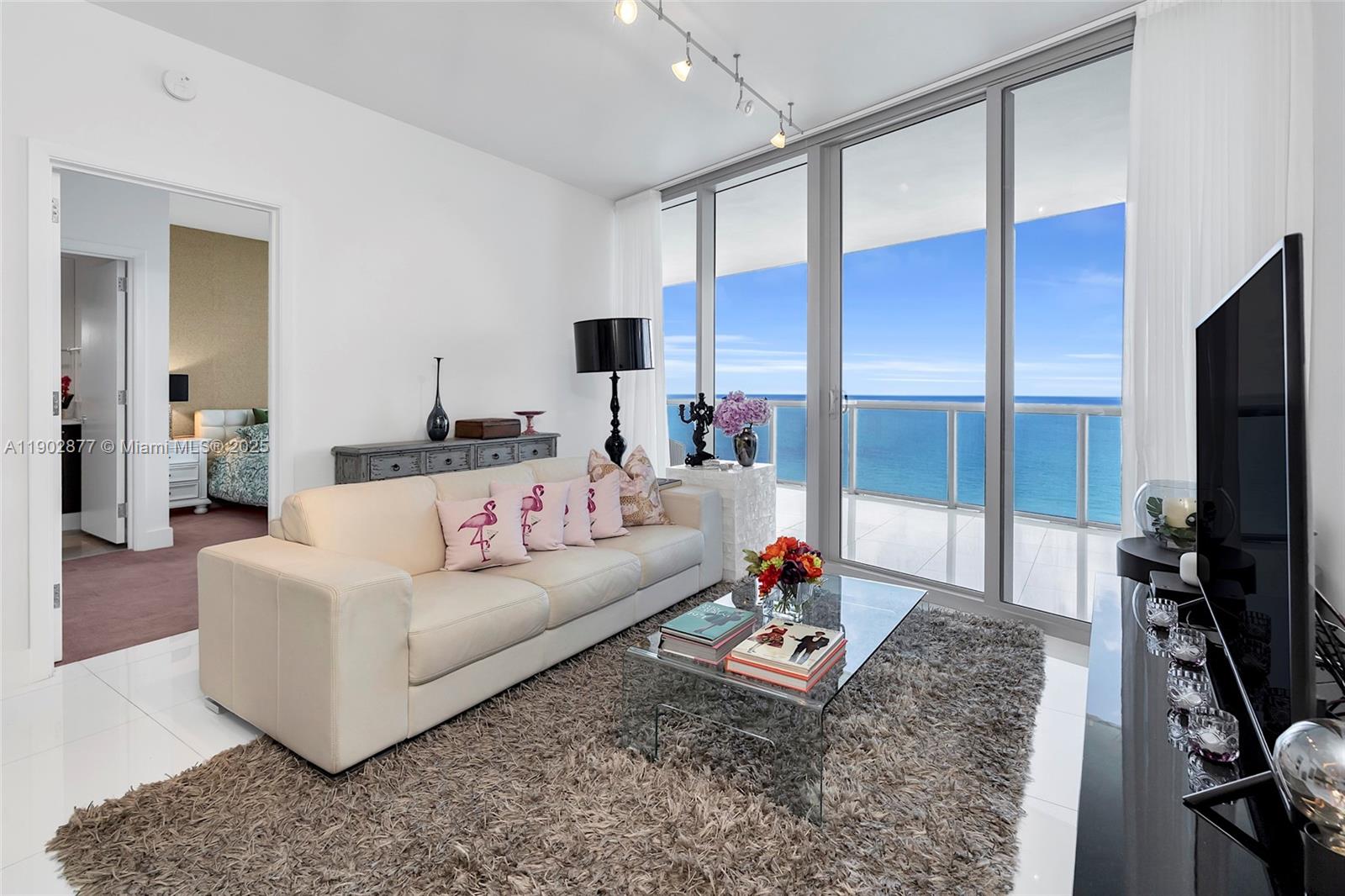 17121 Collins Avenue, Unit 2906 Sunny Isles Beach, FL 33160 - Photo 2 of 42 a living room with furniture flat screen tv and a view of kitchen