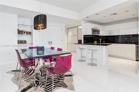 a kitchen with stainless steel appliances kitchen island granite countertop a sink a stove a microwave oven a dining table and chairs with white cabinets