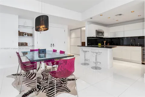 a kitchen with stainless steel appliances kitchen island granite countertop a sink a stove a microwave oven a dining table and chairs with white cabinets