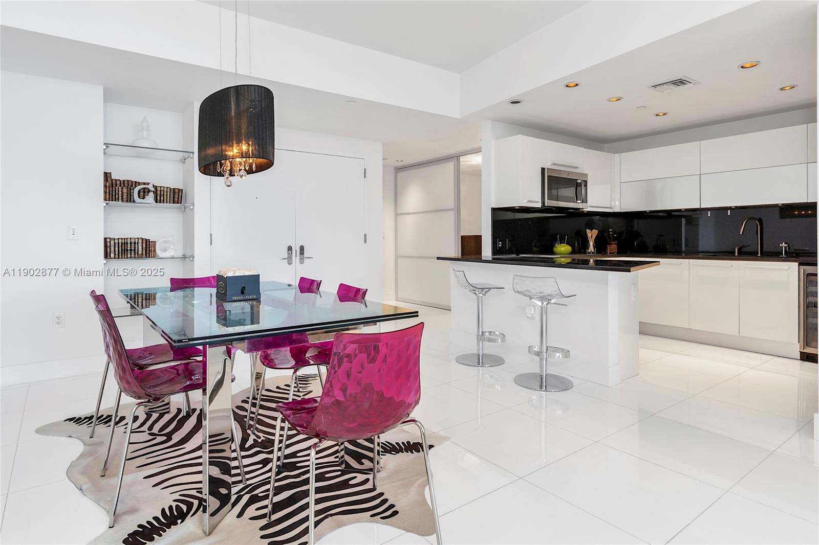 17121 Collins Avenue, Unit 2906 Sunny Isles Beach, FL 33160 - Photo 10 of 42 a kitchen with stainless steel appliances kitchen island granite countertop a sink a stove a microwave oven a dining table and chairs with white cabinets