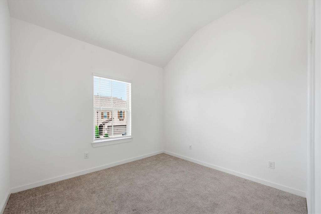 1153 Queensdown Way Forney, TX 75126 - Photo 15 of 26 Carpeted interior space featuring white walls, a vaulted ceiling, and a single window with blinds