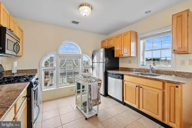 a large kitchen with stainless steel appliances granite countertop a stove a sink dishwasher and a microwave oven with cabinets