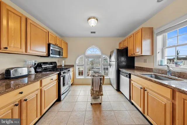 a kitchen with stainless steel appliances granite countertop a stove top oven a sink a counter space and cabinets
