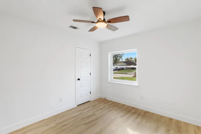 an empty room with window and ceiling fan