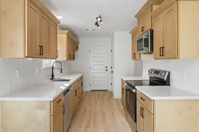a kitchen with stainless steel appliances granite countertop a sink stove and refrigerator
