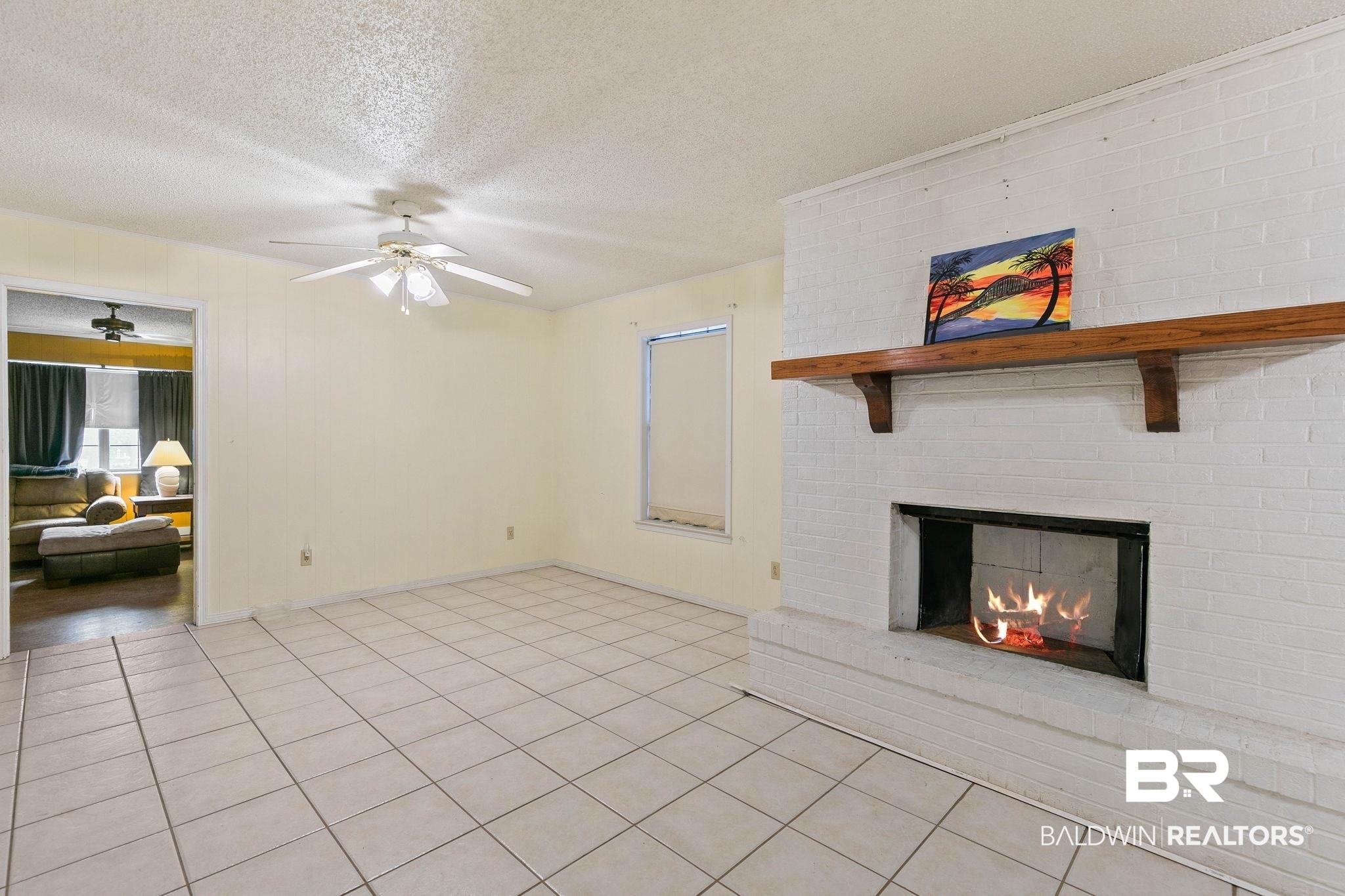 13653 Roberts Road Loxley, AL 36551 - Photo 11 of 33 Living area featuring a painted brick fireplace with a wood mantle, an open hearth, and ceramic tile flooring