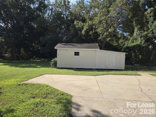a view of a white house with a big yard and large trees