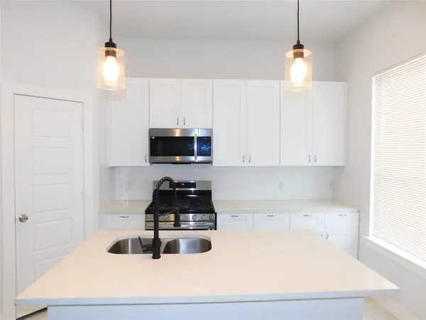 a kitchen with granite countertop a sink a stove and a microwave