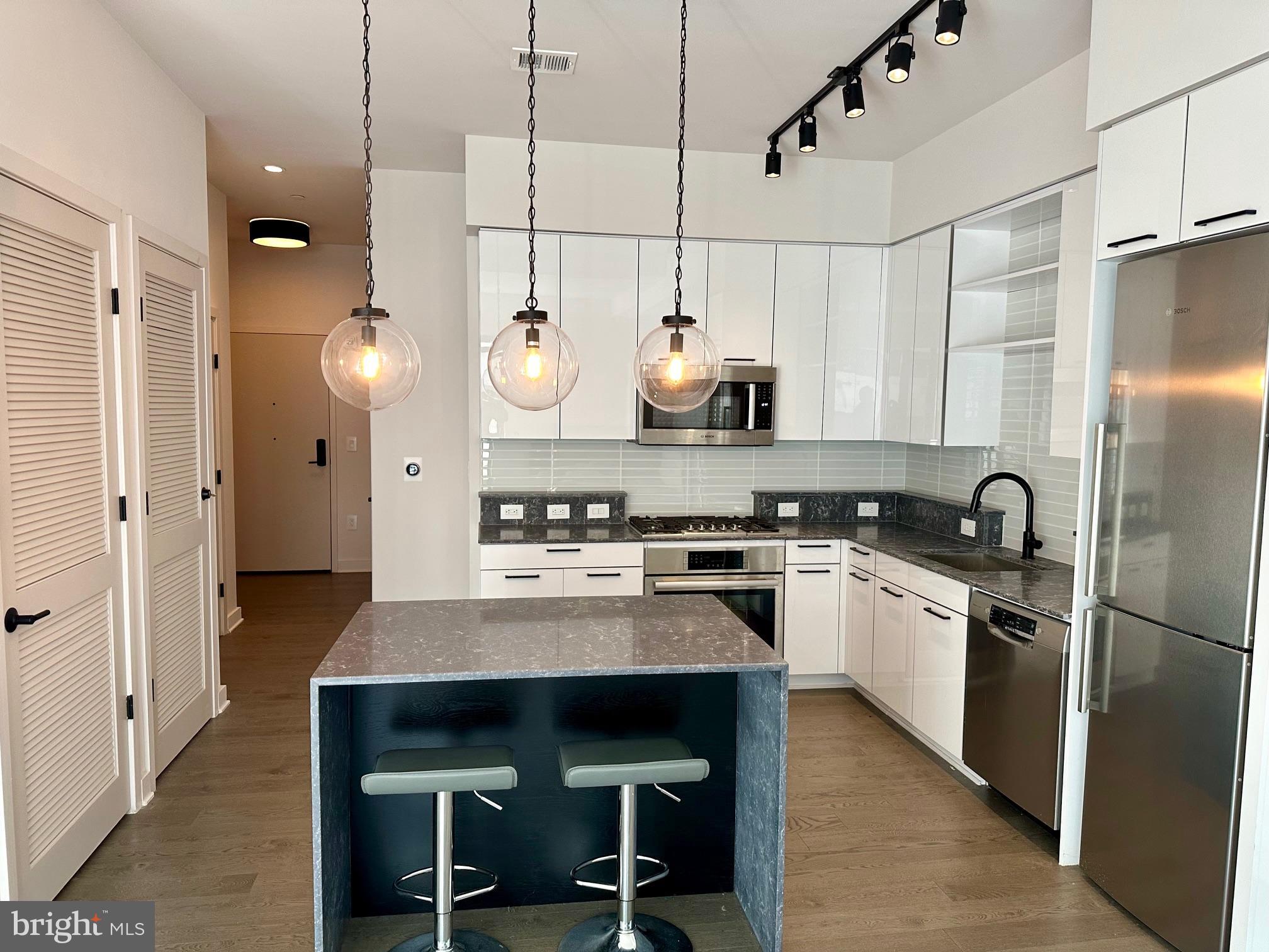 70 N Street Southeast, Unit N215 Washington, DC 20003 - Photo 3 of 16 a kitchen with stainless steel appliances a stove a refrigerator and chairs