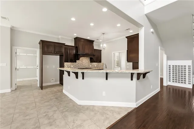 a large white kitchen with stainless steel appliances granite countertop a stove a refrigerator a sink a oven and a refrigerator with wooden floor