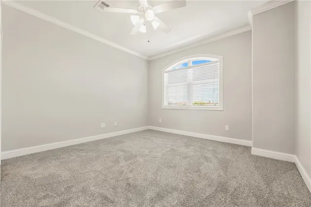 an empty room with a chandelier fan and windows