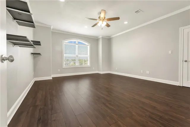 an empty room with wooden floor chandelier fan and windows