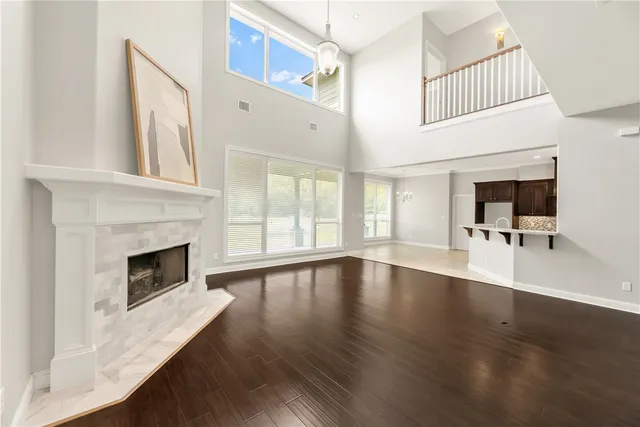 a view of an empty room with wooden floor and a fireplace