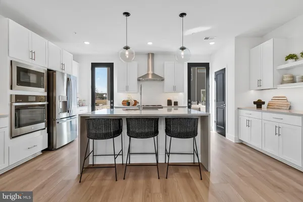 a kitchen with kitchen island a stove a chandelier and wooden cabinets