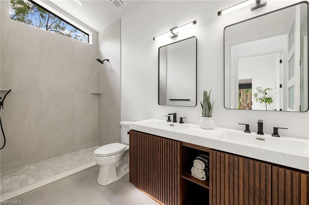 4521 3rd Avenue Northwest Naples, FL 34119 - Photo 22 of 46 a bathroom with a double vanity sink toilet and mirror