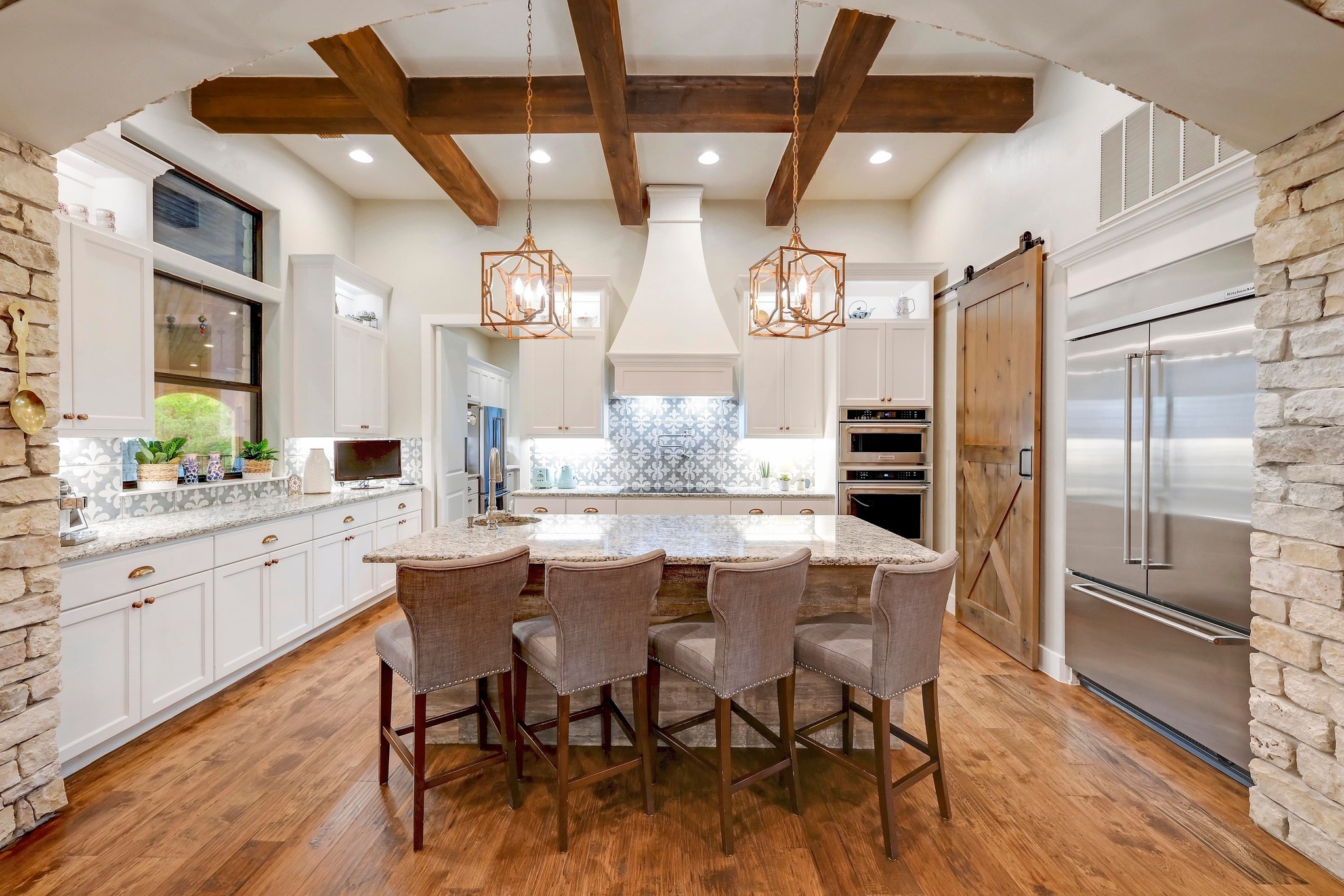401 Trail Ridge Road Wimberley, TX 78676 - Photo 8 of 34 Kitchen featuring pendant lighting, white cabinets, an island with sink, a kitchen bar, and beam ceiling
