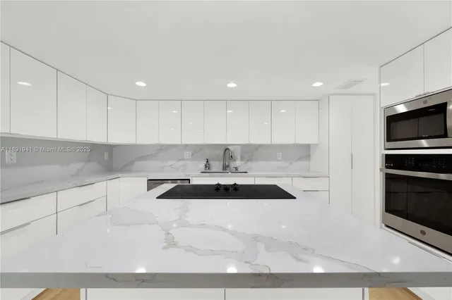a kitchen with granite countertop a sink and a stove top oven with white cabinets