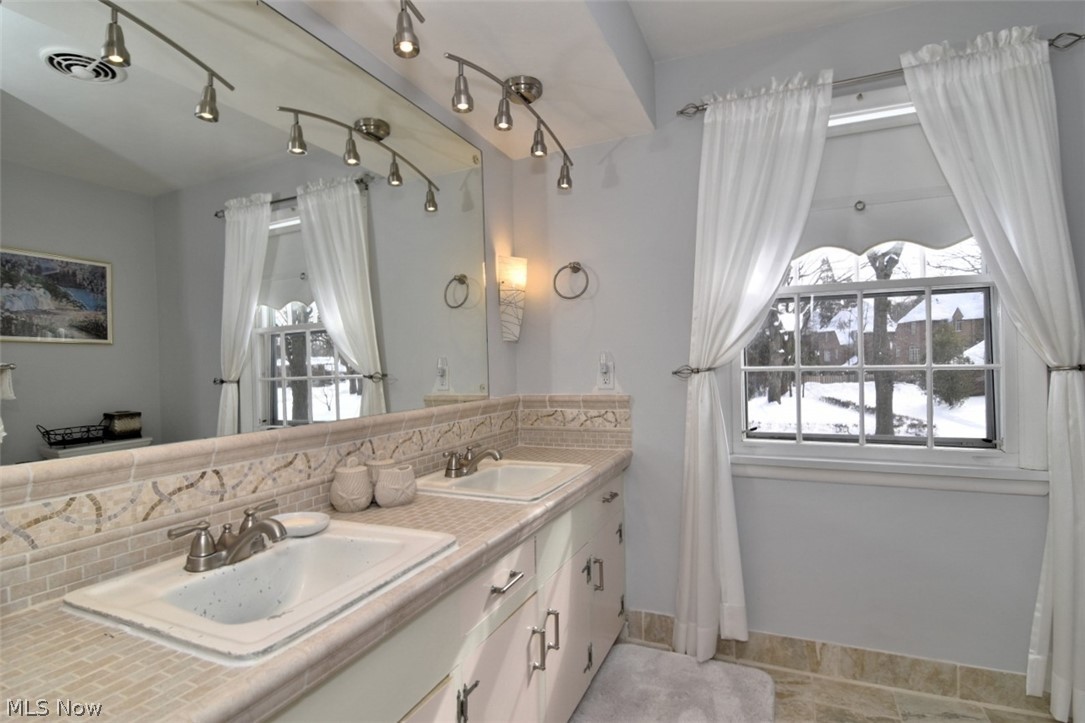 15991 Henley Road Cleveland, OH 44112 - Photo 22 of 36 Full bathroom featuring decorative backsplash, double vanity, and track lighting - main bedroom