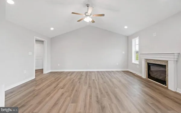 a view of empty room with kitchen and fireplace