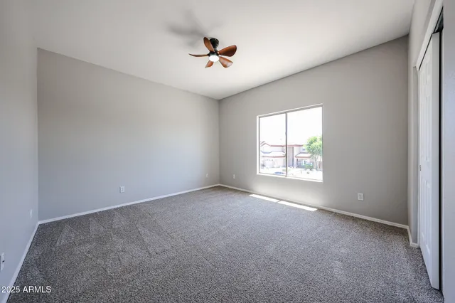 an empty room with windows and ceiling fan