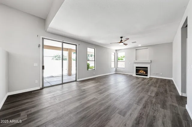 an empty room with wooden floor fireplace and windows