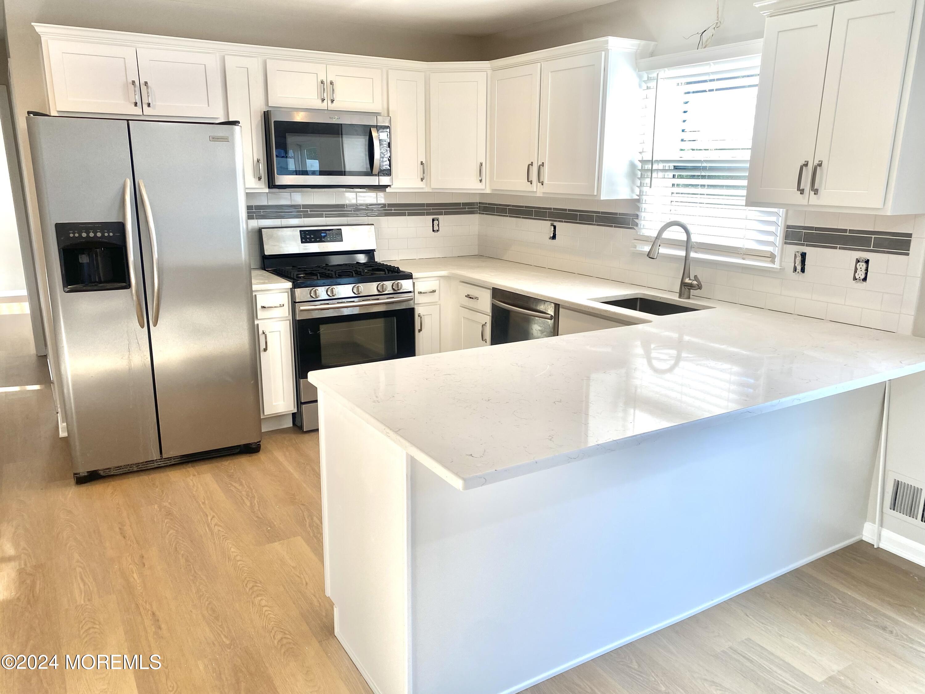 108 Chatham Lane, Unit B Point Pleasant, NJ 08742 - Photo 2 of 14 a kitchen with stainless steel appliances a refrigerator a sink a stove a microwave and island