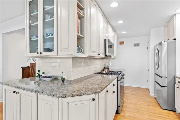 a kitchen with stainless steel appliances granite countertop a sink and dishwasher refrigerator stove and wooden cabinets