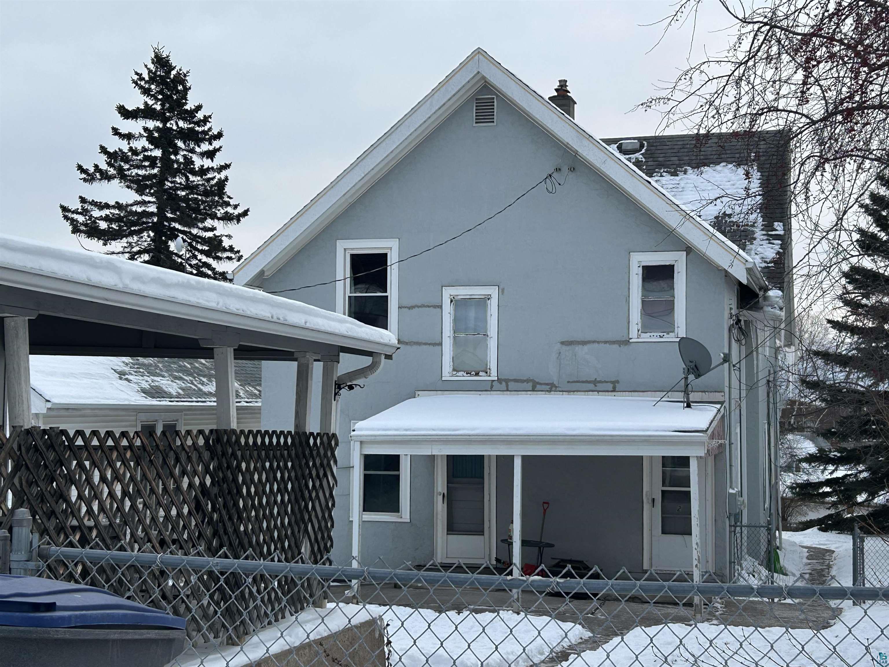 4405 West 7th Street Duluth, MN 55807 - Photo 7 of 18 Rear view of property with stucco siding, a fenced front yard, and a chimney