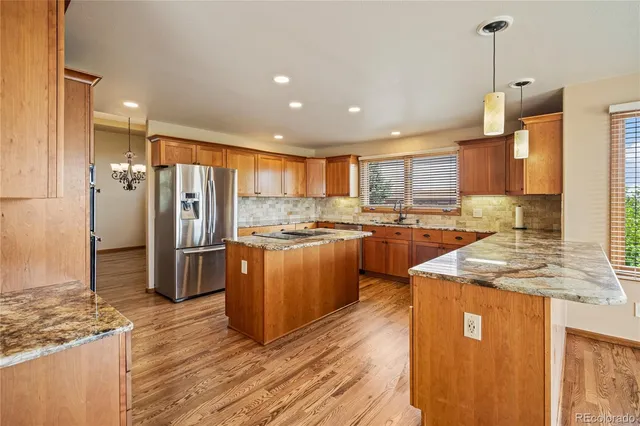 a kitchen with stainless steel appliances granite countertop a refrigerator a sink and a stove