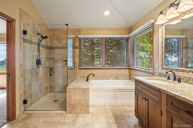 a bathroom with a granite countertop sink a large mirror a bathtub and next to a window