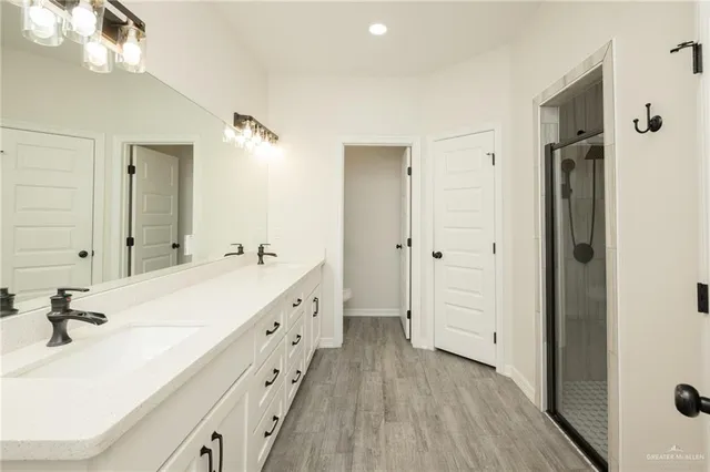 a spacious bathroom with a double vanity sink a mirror and a shower