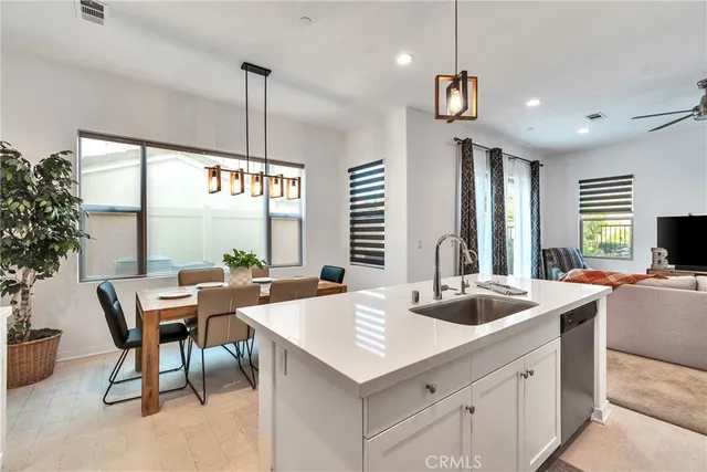 a kitchen with a stove a kitchen island a sink dishwasher a dining table and chairs with wooden floor