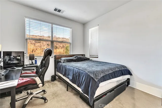 a bedroom with a bed a desk and chair with window