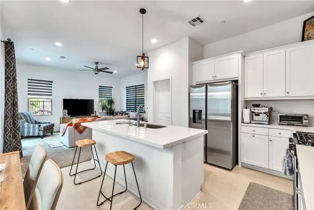 a kitchen with stainless steel appliances kitchen island a stove a refrigerator a oven a sink a dining table and chairs with wooden floor