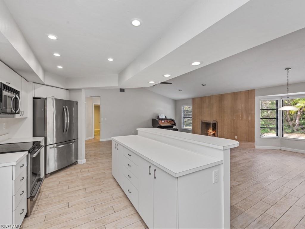 7016 Trail Boulevard Naples, FL 34108 - Photo 11 of 25 a large white kitchen with wooden floor and stainless steel appliances