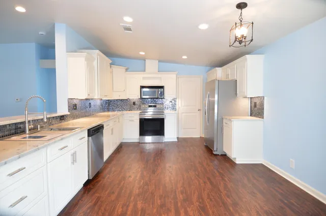 a large kitchen with cabinets wooden floor and stainless steel appliances