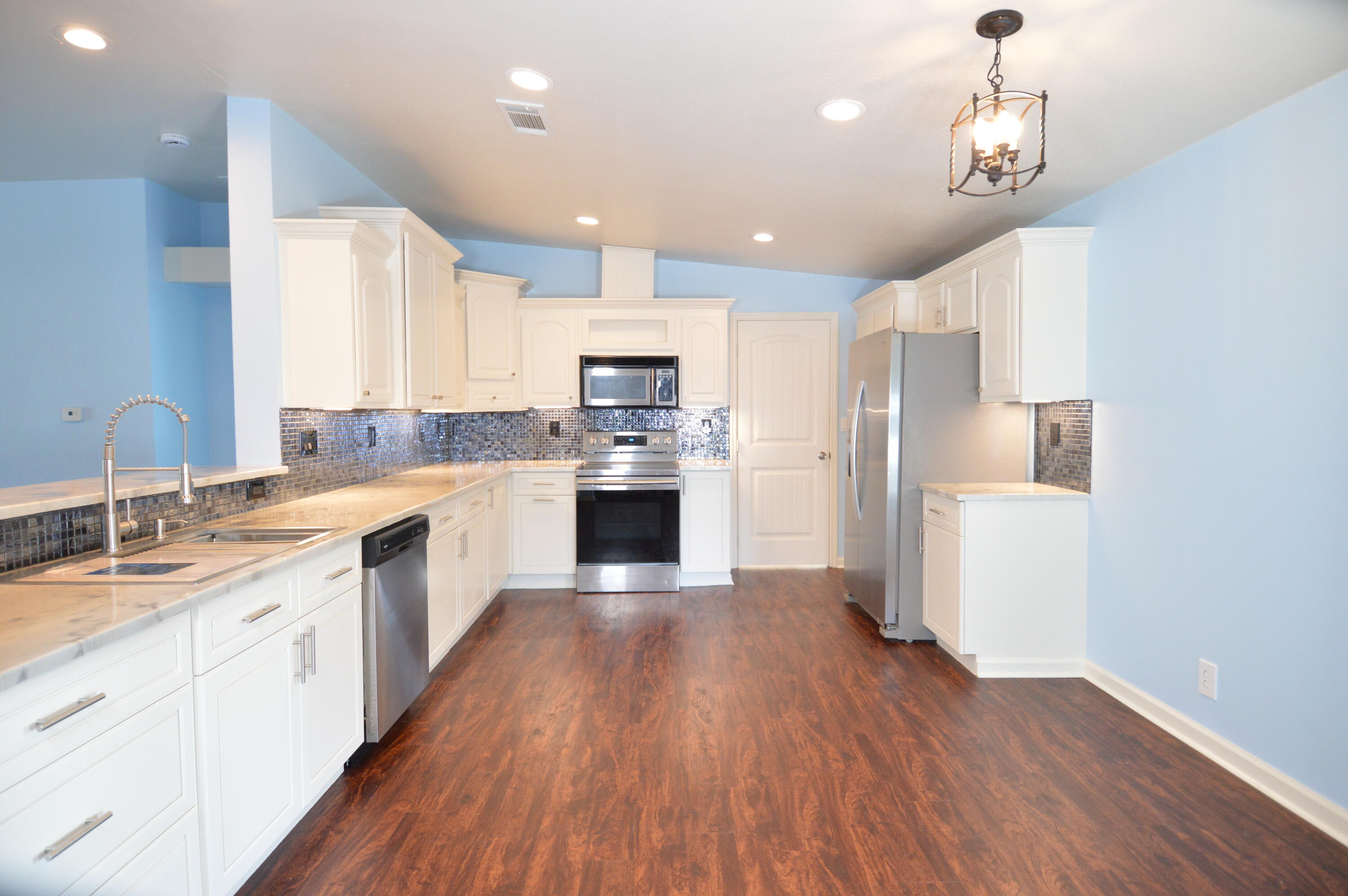 a large kitchen with cabinets wooden floor and stainless steel appliances