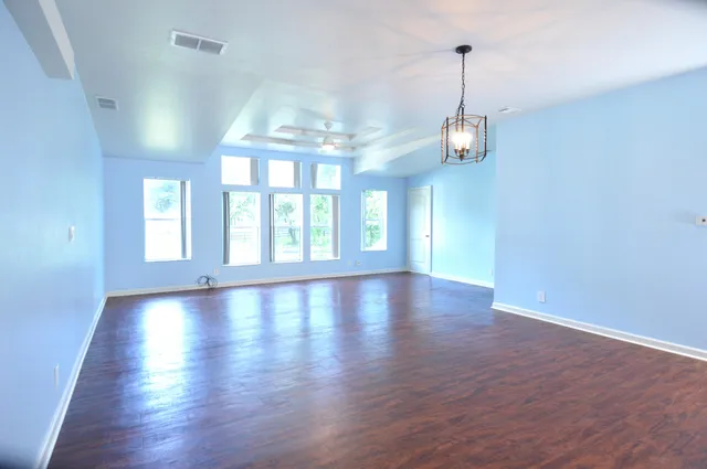 a view of a room with wooden floor large windows and a chandelier