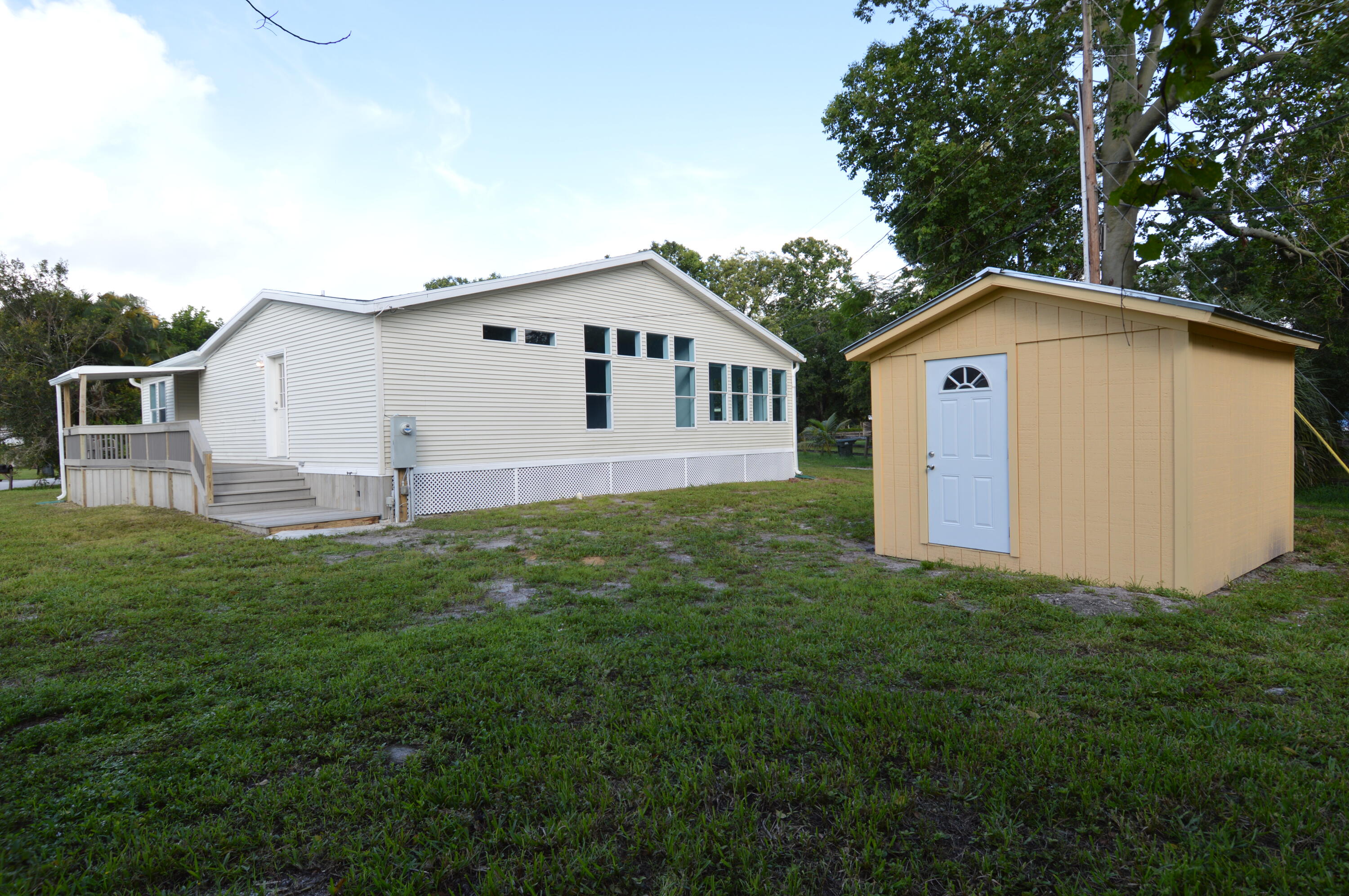1201 Southwest Sunshine Street Stuart, FL 34997 - Photo 33 of 41 a white house with a small yard and big trees
