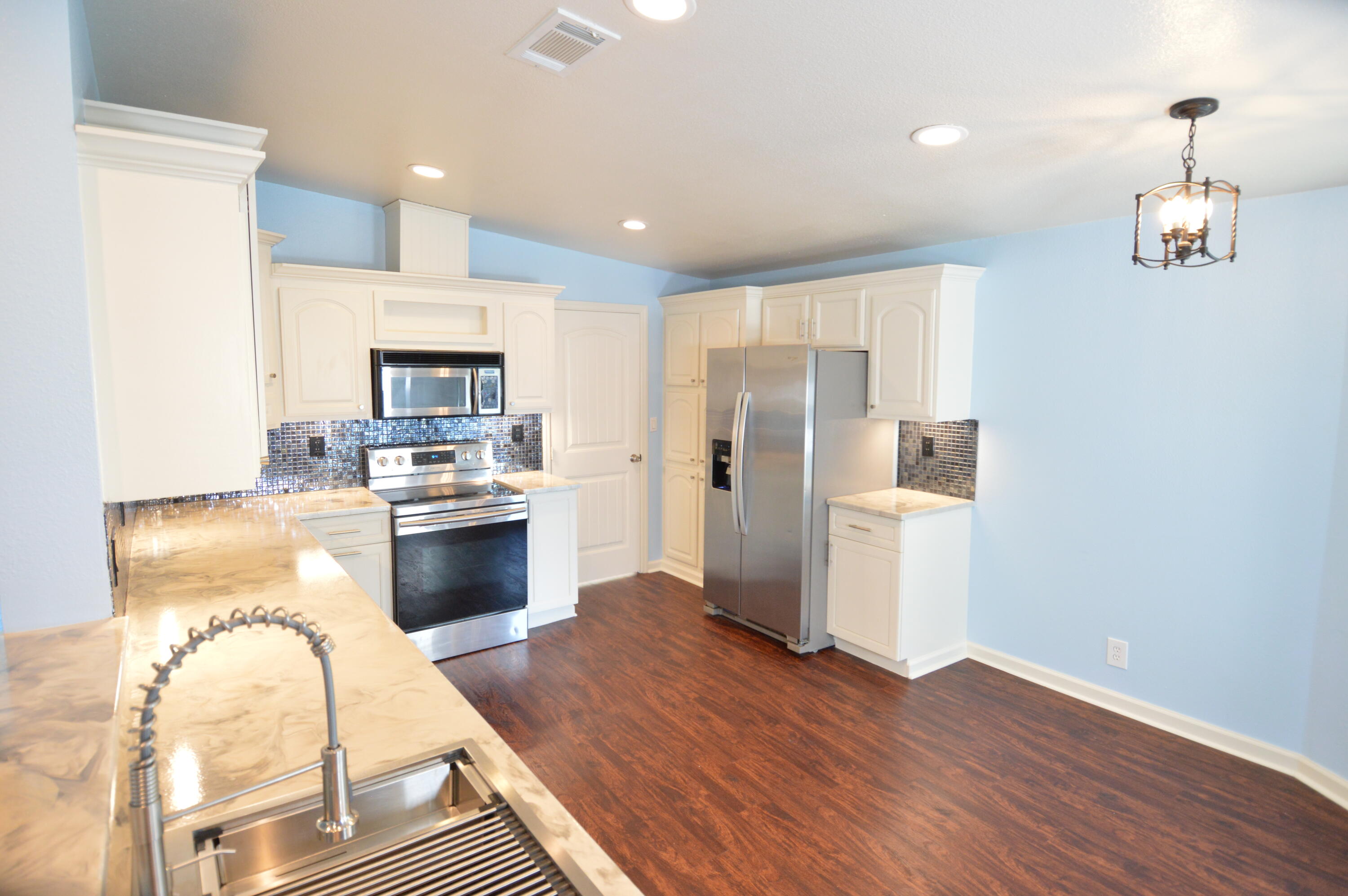 1201 Southwest Sunshine Street Stuart, FL 34997 - Photo 10 of 41 a kitchen with stainless steel appliances kitchen island granite countertop a refrigerator a stove top oven and a sink with wooden floor