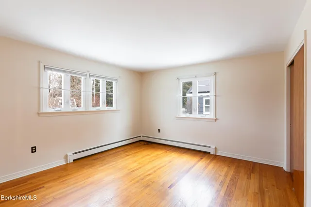 a view of an empty room with a window and wooden floor